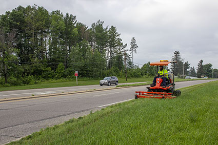 A county highway worker mows alongside a state highway in Eau Claire.