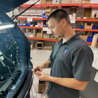 Technician working on wiring in the trunk of a patrol vehicle.