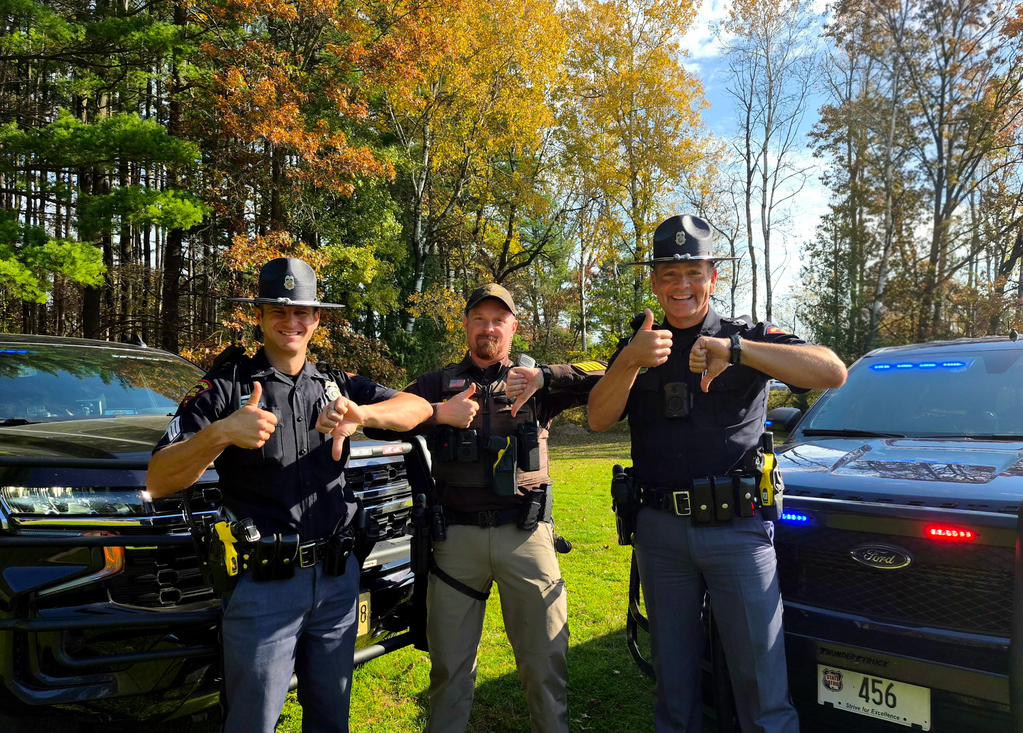 Officers from Wisconsin State Patrol and Marquette County Sheriff's Office posing with one thumb up and one thumb down