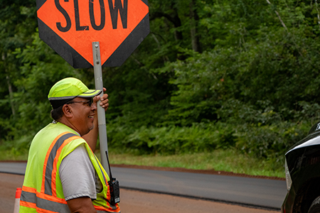 A flagger wearing PPE and holding a "SLOW" sign