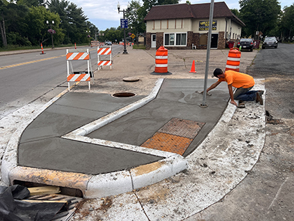 A worker applies the finishing touches to a new curb ramp.
