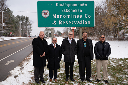 State, federal and tribal leaders stand near the newly installed dual language sign.