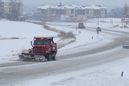 A snow plow clears a snowy road.