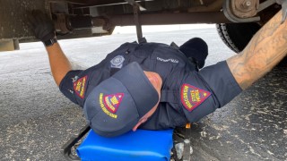 Wisconsin State Patrol motor carrier inspector underneath a school bus performing an inspection