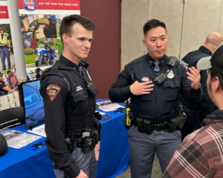 Wisconsin State Patrol troopers at a recruitment booth talking with a community member