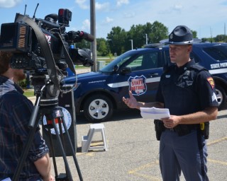 Member of the media with a camera interviewing a Wisconsin State Patrol officer