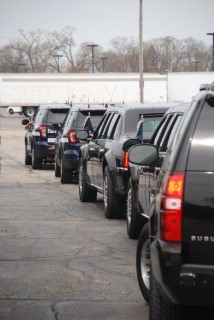 US Secret Service vehicles in a row behind two State Patrol cruisers 