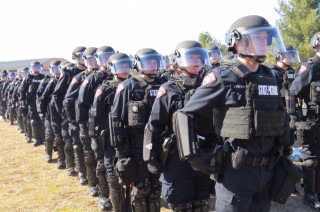 Dozens of WSP mobile field force officers in riot gear standing in a row at attention