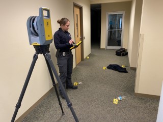 A female WSP officer reading data from a display while using a total station mapping an indoor crime scene
